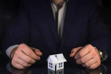 Businessman hands and paper house on table. Real estate concept