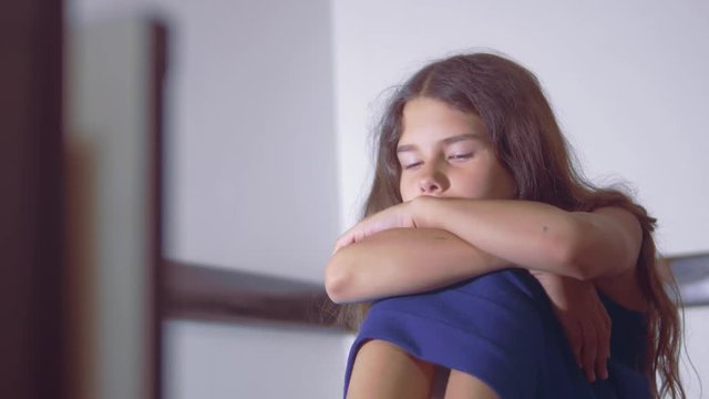 sad girl upset embraces her feet. is depressed and suicidal little lamentable girl schoolgirl sadness misses the night in bed concept lifestyle childhood family. the problem of education in the family