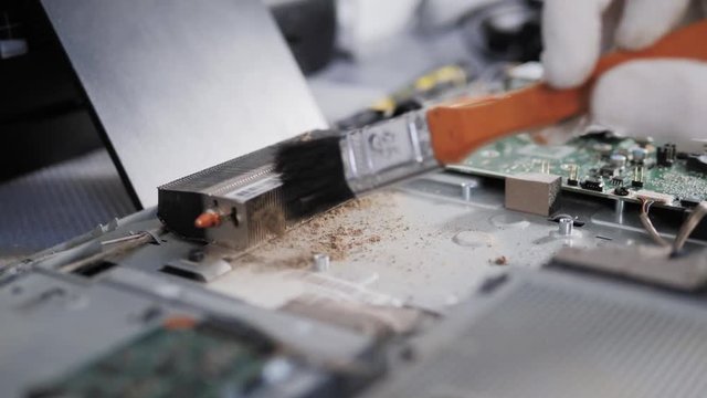 Closeup shot of male hands working on disassembling and cleaning circuit board in laptop using brush repair pc processor and change cooler
