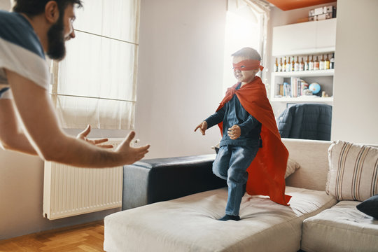 Father playing with son dressed up as superhero