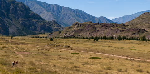 The concept of outdoor activities on weekend or holiday - beautiful view of the valley, when a group of tourists goes to the mountains.