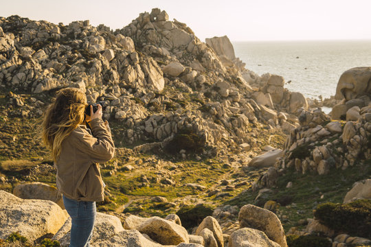 Italy, Sardinia, woman on a hiking trip taking a picture at the coast