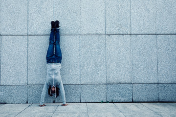 female hipster doing a handstand against wall
