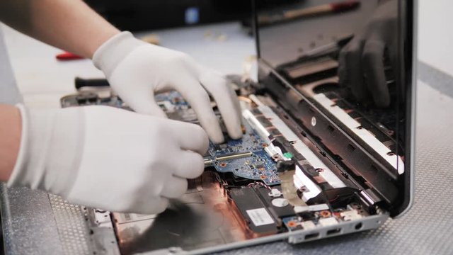 Closeup shot of male hands working on disassembling and cleaning circuit board in laptop using brush repair pc processor and change cooler