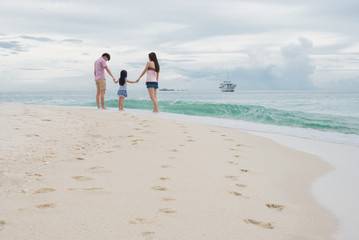 Happy young family having fun running on beach . Family traveling concept