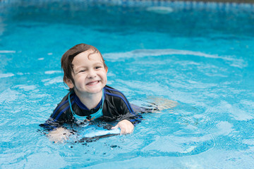 Boy playing in outdoor swimming pool. Kids  practicing swim with foam pad.