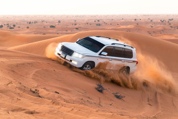 Obraz na płótnie Canvas safari on jeeps SUVs in the Arab orange-red sands in the sunset sun. column of sand of wheels, 