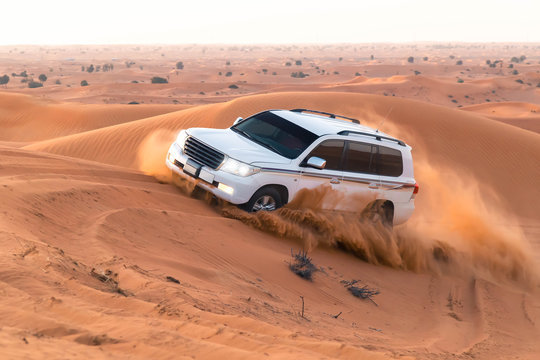Fototapeta safari on jeeps SUVs in the Arab orange-red sands in the sunset sun. column of sand of  wheels, 