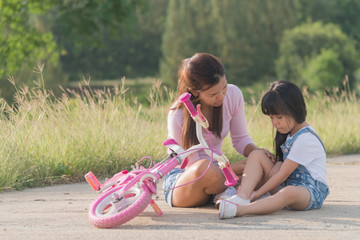 mother helping her daughter has accident while practice to riding a bicycle