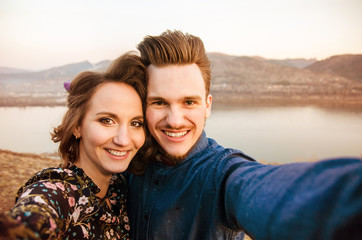 Obraz premium Couple in love do selfie on hills and river background.