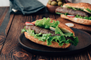 Hot dog with sausage grill, fresh vegetables and sauce. Toned image.