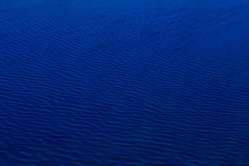 Fototapeta na wymiar The dark shadow blue water surface has waves pattern for use as background and texture.