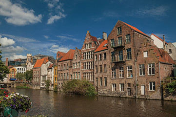 Fototapeta na wymiar Old buildings in front of the canal with blue sky in the City Center of Ghent. In addition to intense cultural life, the city is full of Gothic and Flemish style buildings. Northern Belgium.