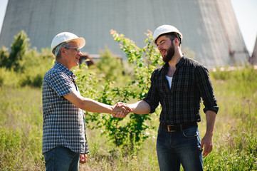 two power line tower workers with handshaking