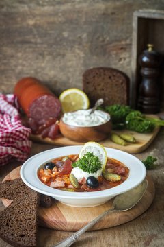 Solyanka (Traditional Russian meat soup from different kinds of meat and sausages with pickled cucumber and lemon)