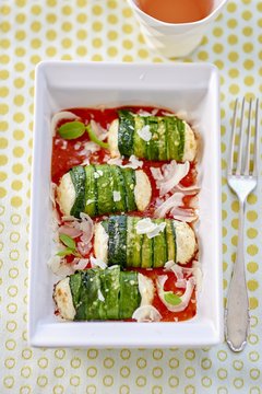 Zucchini rolls with fresh cheese filling on tomato sauce