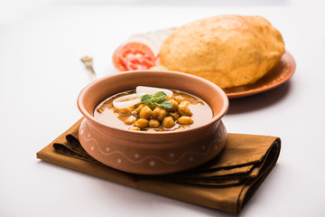 Chole Bhature or Chick pea curry and Fried  Puri served in terracotta crockery over white background. selective focus