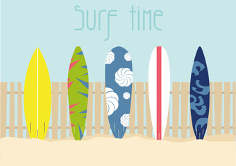 The surfboards on the sand are standing against the fences.