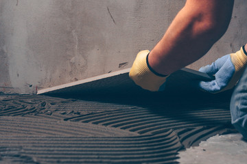 Working tiler puts on the floor a large square tile of ceramic granite