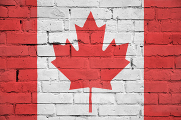 Canada flag is painted onto an old brick wall