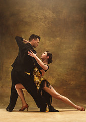 Dance ballroom couple in gold dress dancing on studio background. - obrazy, fototapety, plakaty