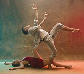 Flexible young modern dance couple posing in studio.