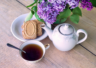 
Lilac flowers with tea and cookies on the table