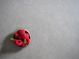 Red raspberry, in a ceramic bowl, on a gray background