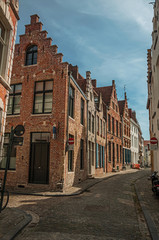 Obraz premium Empty street with brick buildings in Flanders’s typical style and blue sky at Bruges. With many canals and old buildings, this graceful town is a World Heritage Site of Unesco. Northwestern Belgium.
