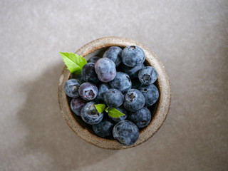 Fresh blueberries, in a ceramic bowl, on a gray background