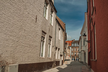 Fototapeta na wymiar Quite empty street with brick buildings and blue sky at Bruges. With many canals and old buildings, this graceful town is a World Heritage Site of Unesco. Northwestern Belgium.