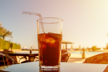 Cuba Libre cocktail and ice in glass sunrise
