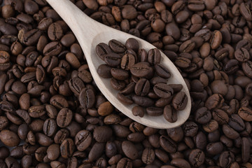 A wooden spoon with coffee beans as background. Close up  