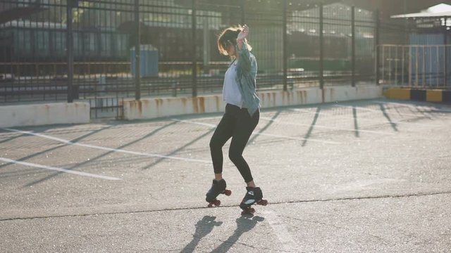 Attractive beautiful young woman riding roller skating and dancing in the streets. Urban background, slow motion 120fps