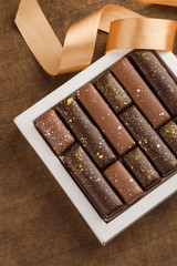 Handmade bonbons with gold splashes in box on wooden background