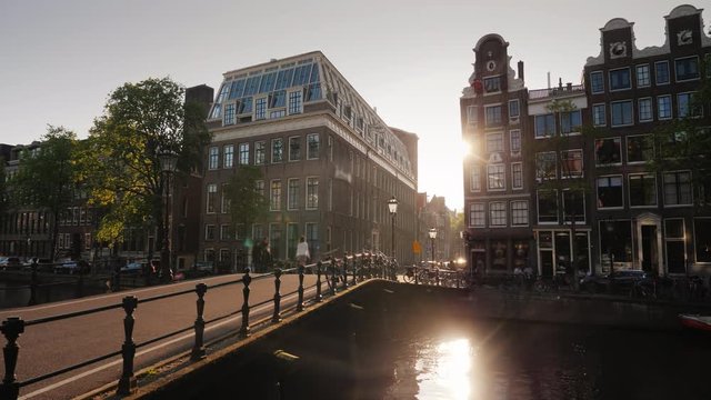 A beautiful sunset in Amsterdam, the sun shines through the houses and is reflected in the water of the canal