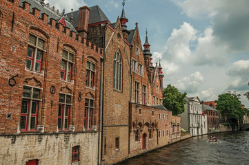 Old brick buildings on the canal's edge in a sunny day at Bruges. With many canals and old buildings, this graceful town is a World Heritage Site of Unesco. Northwestern Belgium.