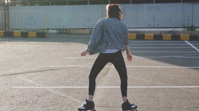 Attractive beautiful young woman riding roller skating and dancing in the streets. Urban background, slow motion 120fps