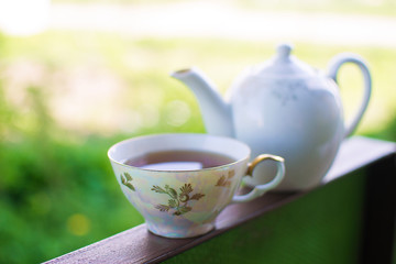 Black tea in glass cup and teapot on summer outdoor background. Copy space.