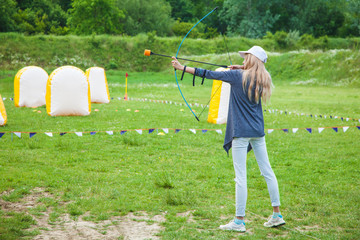 Young blond girl shoots with an arrow