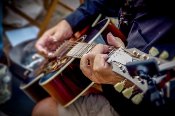 Fototapeta na wymiar Wrinkled hands of man holding and play guitar