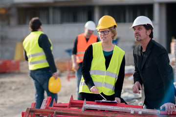 Construction manager and a female engineer wearing safety jacket and helmet checking projects on construction site