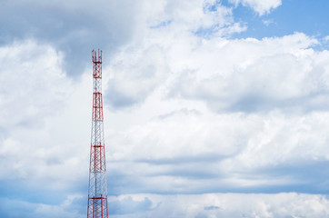Mobile telecommunication tower with communication antennas in the background of dense clouds