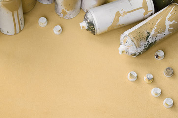 Some used orange aerosol spray cans and nozzles with paint drips lies on a blanket of soft and...