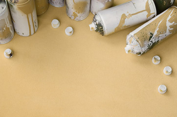 Some used orange aerosol spray cans and nozzles with paint drips lies on a blanket of soft and...