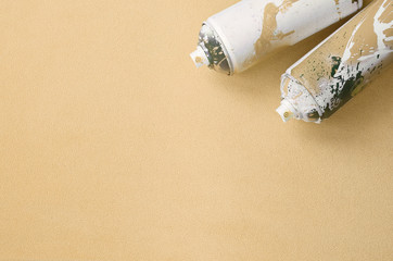 Some used orange aerosol spray cans with paint drips lies on a blanket of soft and furry light...