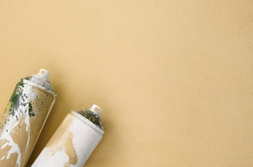 Some used orange aerosol spray cans with paint drips lies on a blanket of soft and furry light...