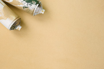 Some used orange aerosol spray cans with paint drips lies on a blanket of soft and furry light...