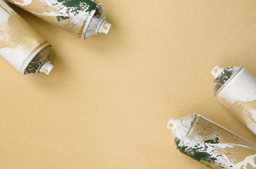 Some used orange aerosol spray cans with paint drips lies on a blanket of soft and furry light...