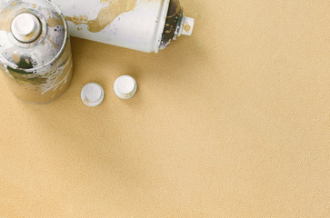 Some used orange aerosol spray cans and nozzles with paint drips lies on a blanket of soft and...